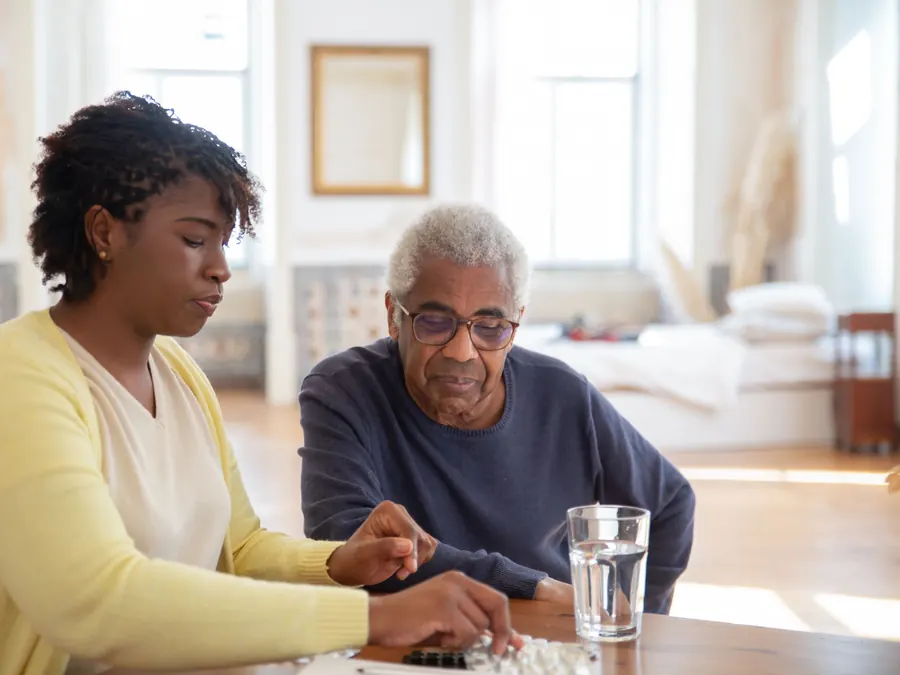 A nurse goes over an older man's medications with him at his dining table